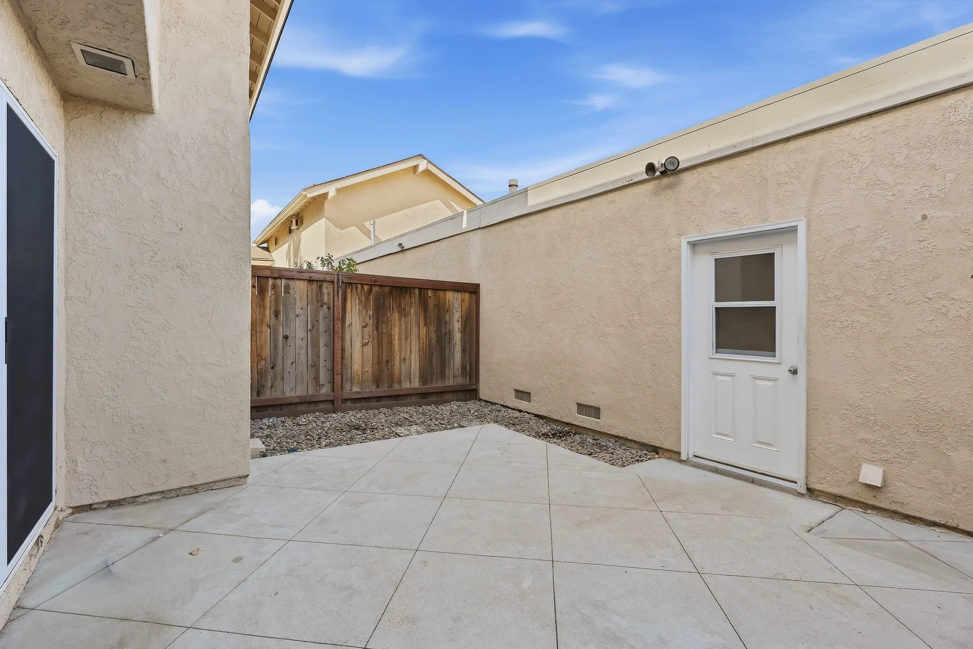 Private patio at 8 Silverwood with a paved concrete surface, gravel border, and wood privacy fence