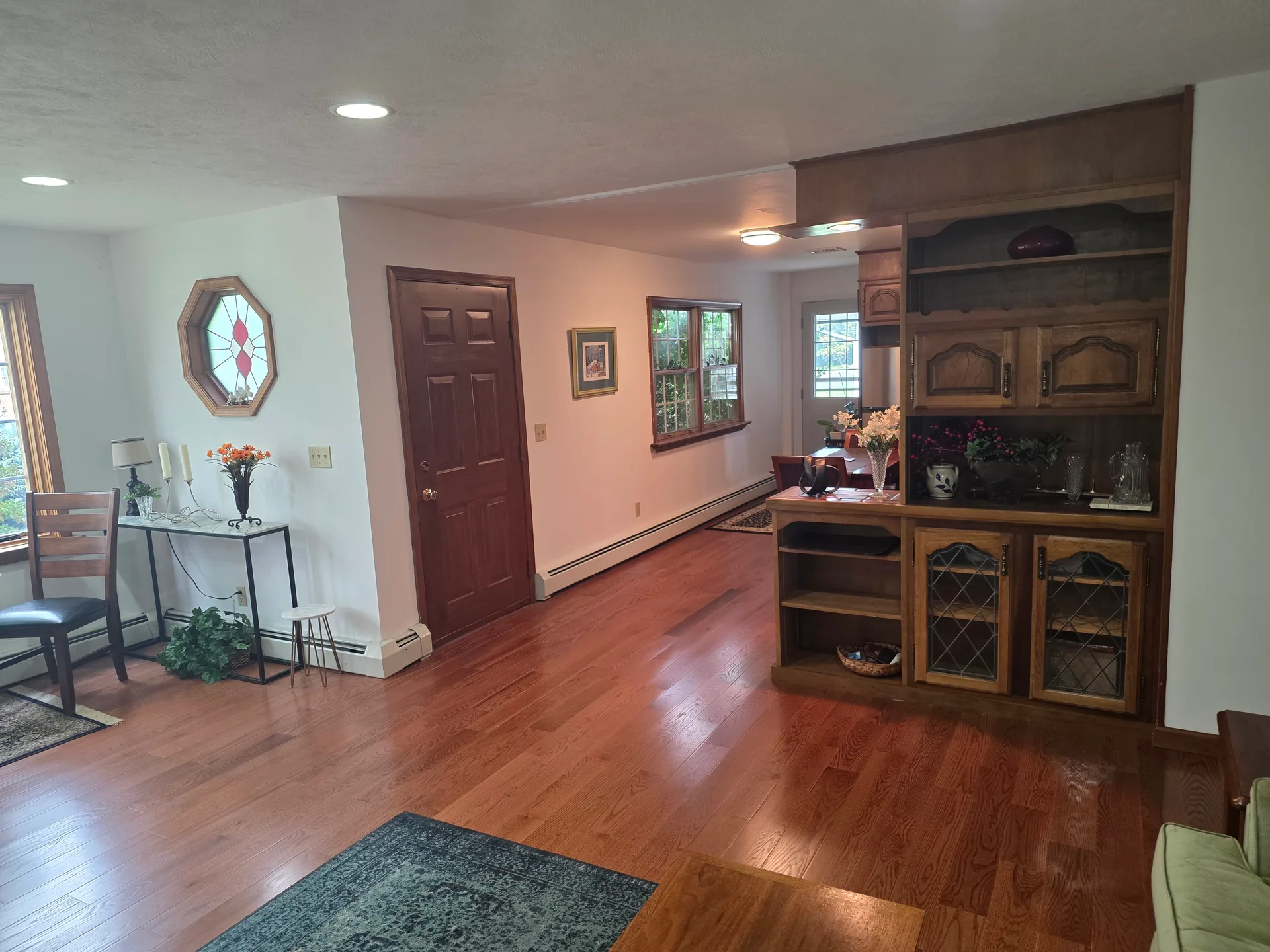 Living room with hardwood floors, white walls, and wood built-in hutch