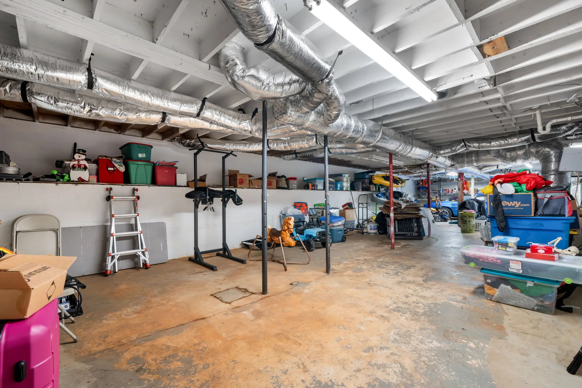 Unfinished walk-out basement with exposed joists and HVAC ducting, ready for a workshop or storage