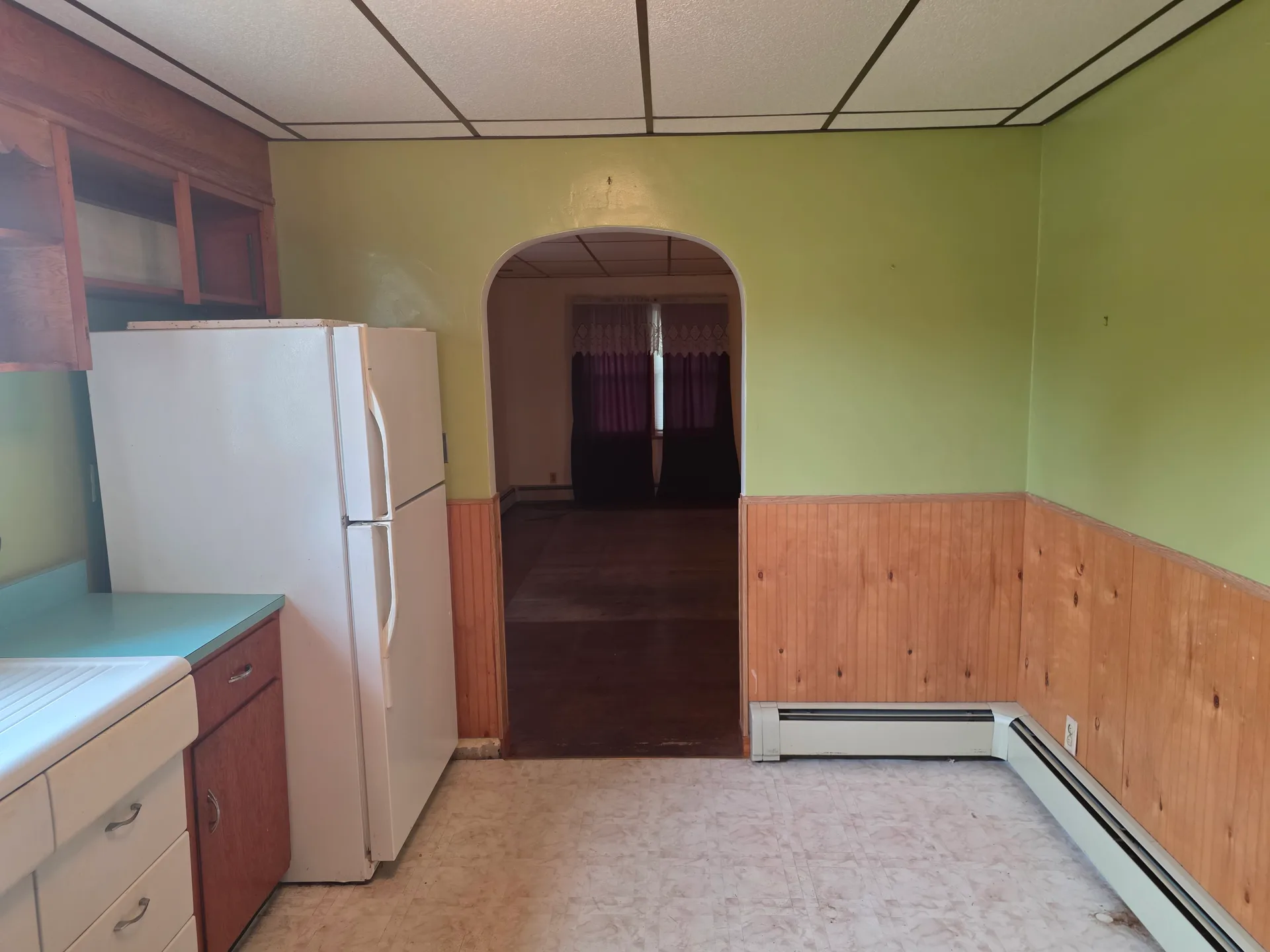 Kitchen with retro green paint, wood wainscoting, and view into adjoining room