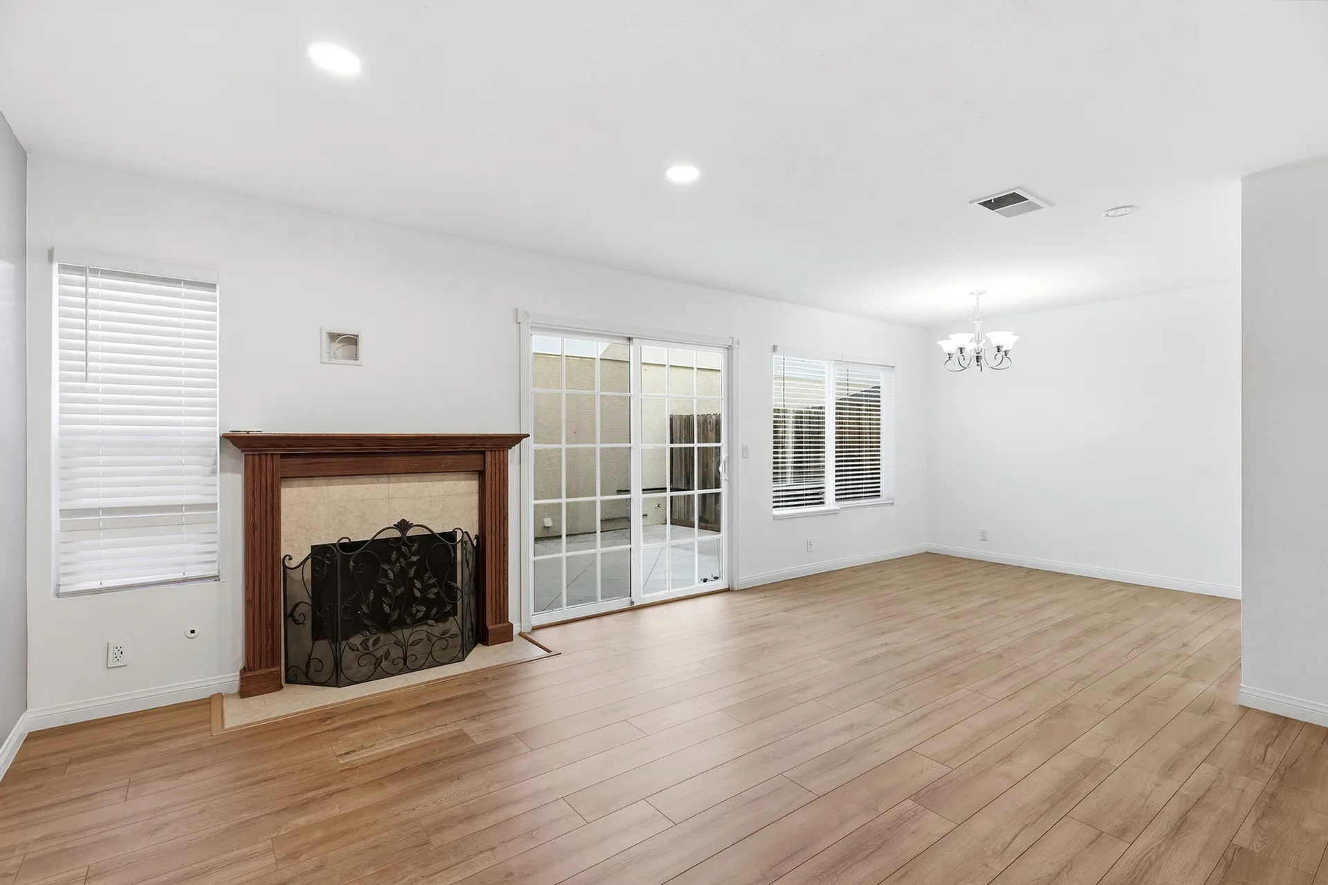 Living room at 8 Silverwood with wood-look flooring, white walls, a wood-mantel fireplace, and a sliding glass door to the patio
