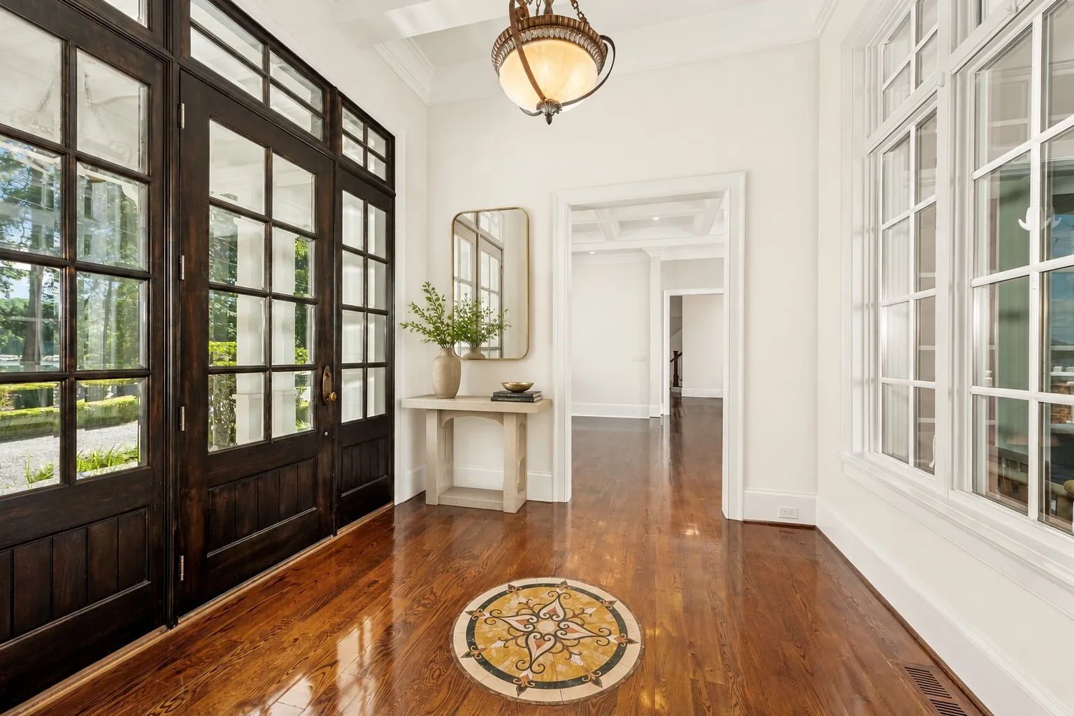 Grand foyer with dark wood double doors and tile inlay