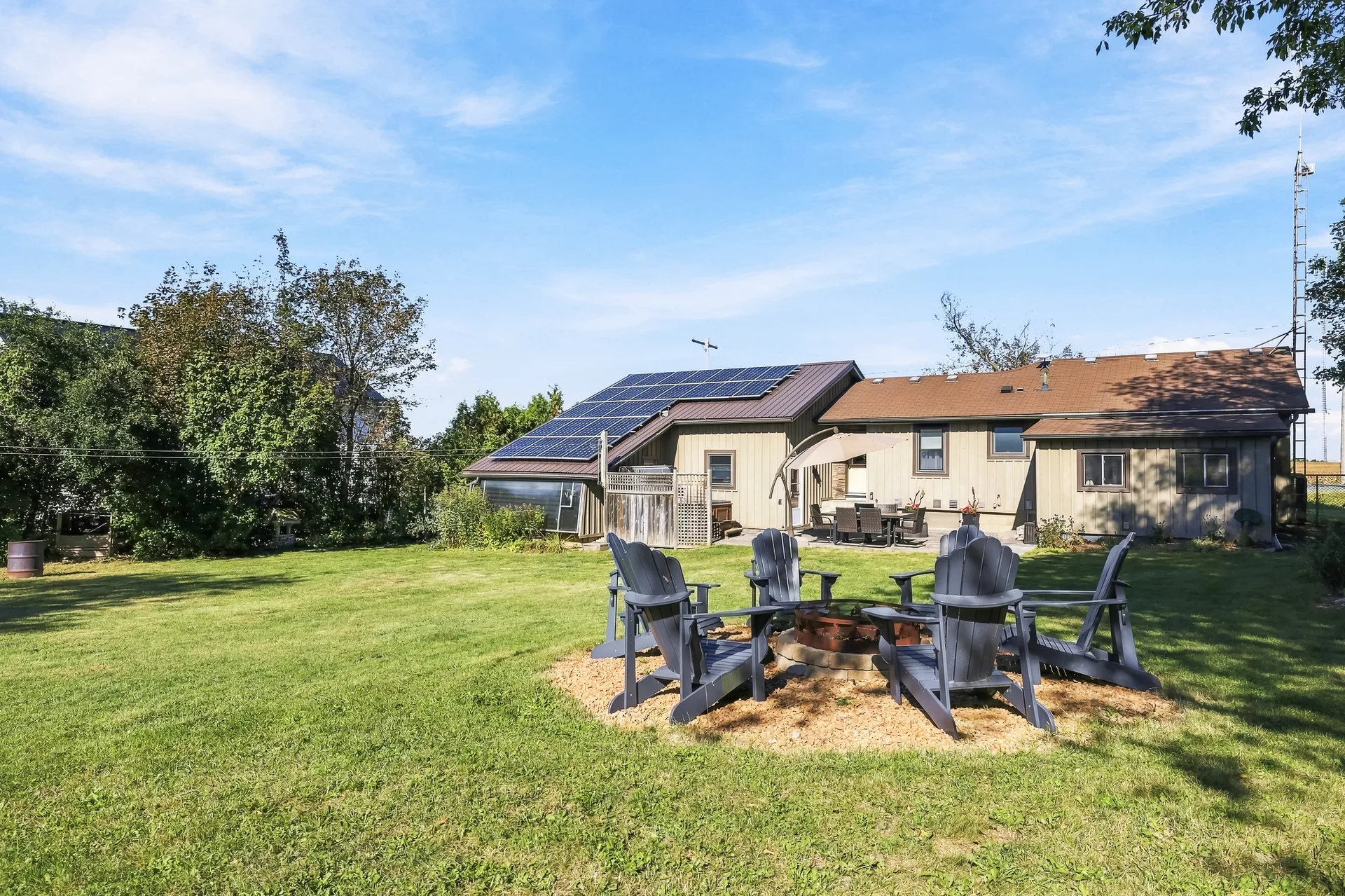 Rear of the home with fire pit seating and solar panels on the roof