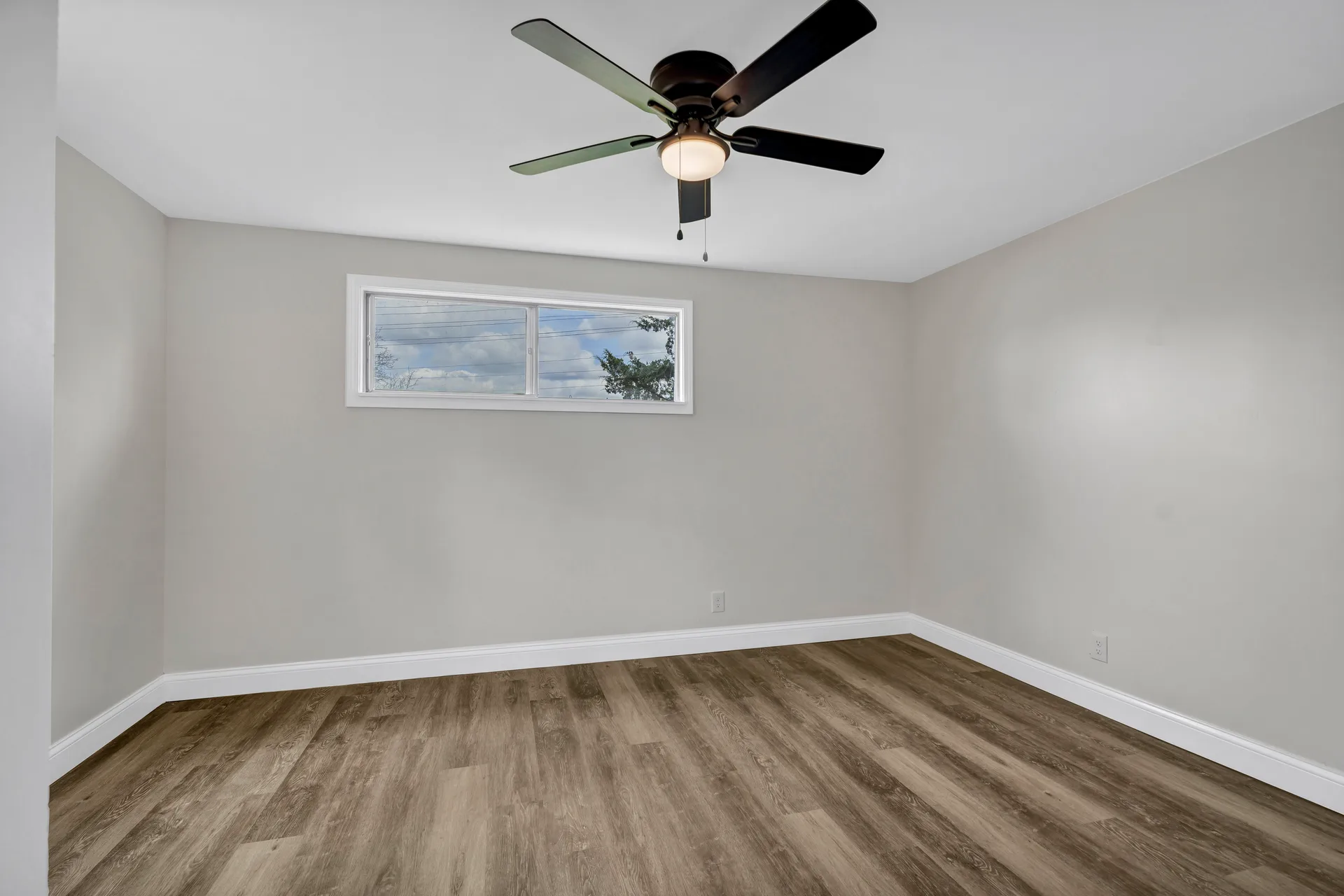 Vacant bedroom with window and vinyl plank flooring