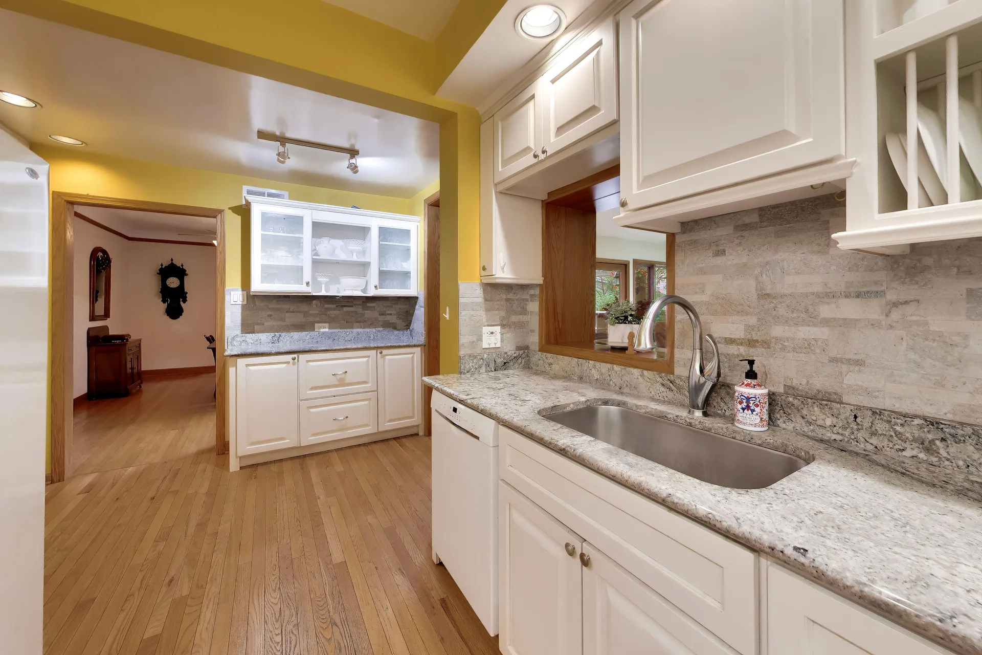 White-cabinet kitchen with granite counters and stone backsplash at 3708 Cooper Place
