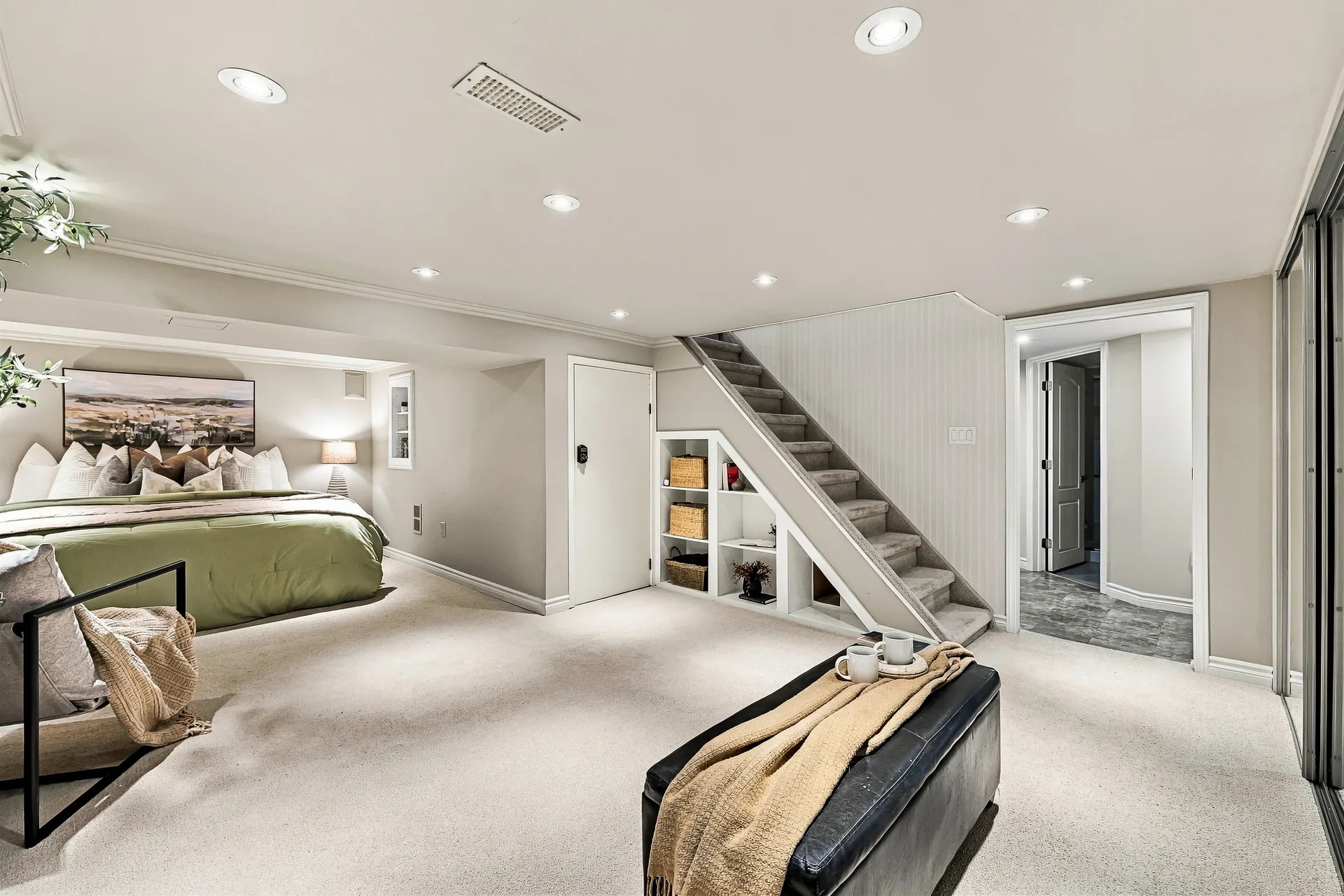 Lower-level primary bedroom with built-in staircase shelving