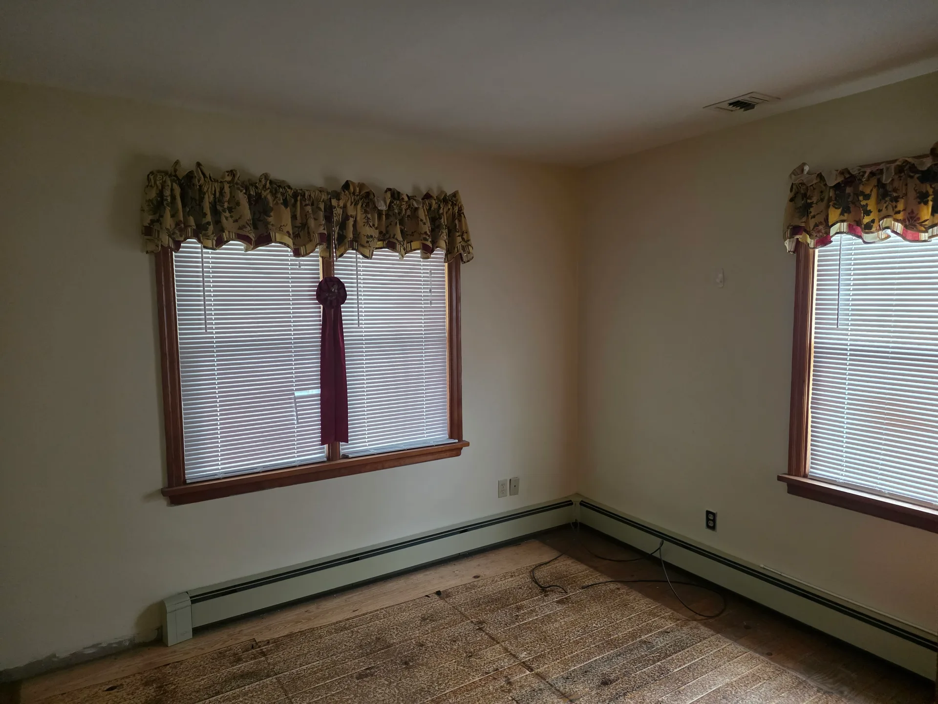 Living room with light-colored walls, wood window trim, and hardwood flooring