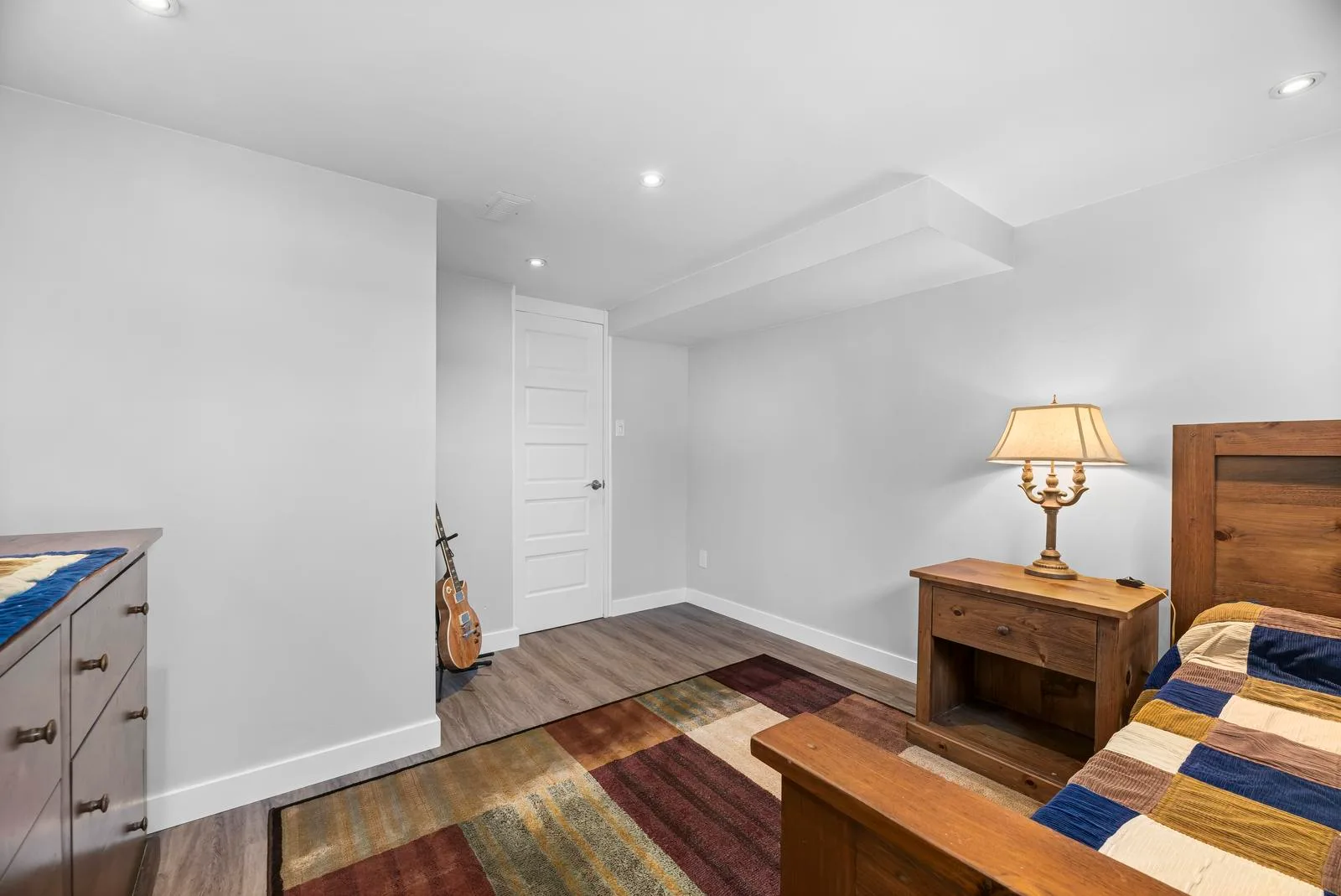 Secondary bedroom with wood-frame bed, neutral walls, and recessed lighting