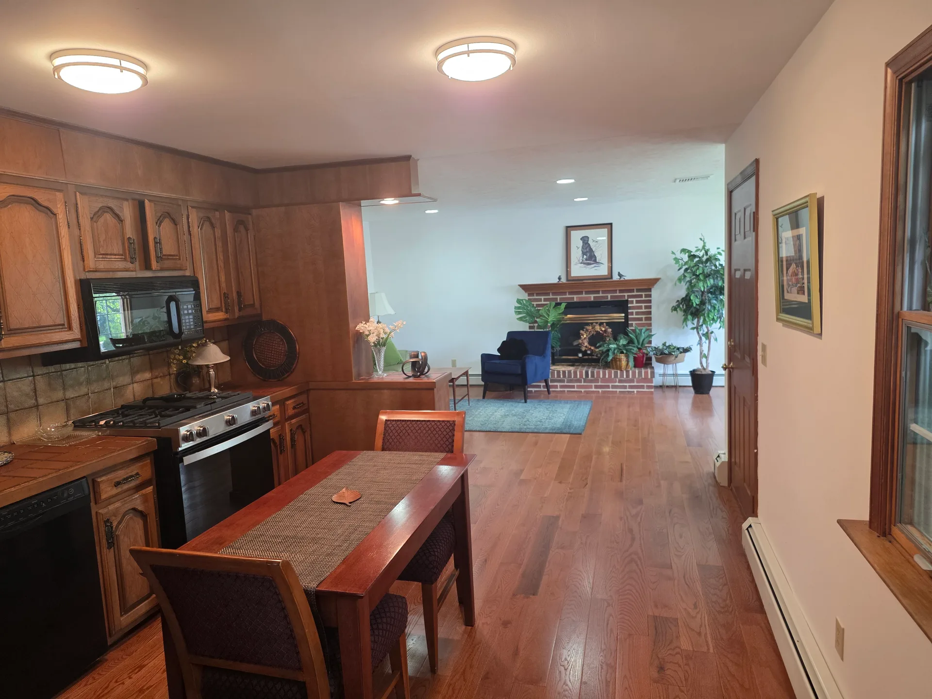 Open-concept kitchen with wood cabinetry and hardwood flooring flowing into living room