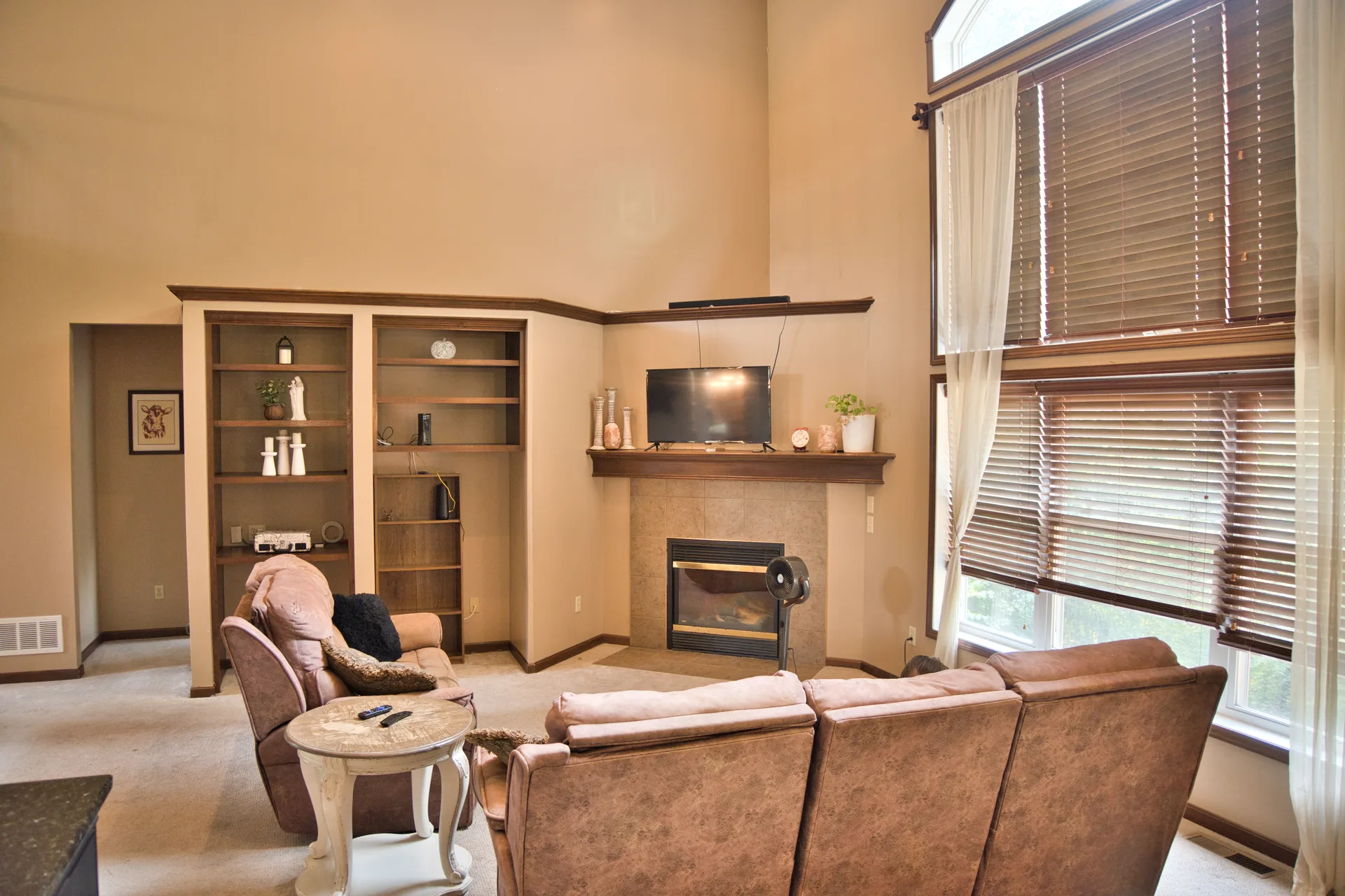 Two-story living room with a stacked-stone fireplace and tall arched windows