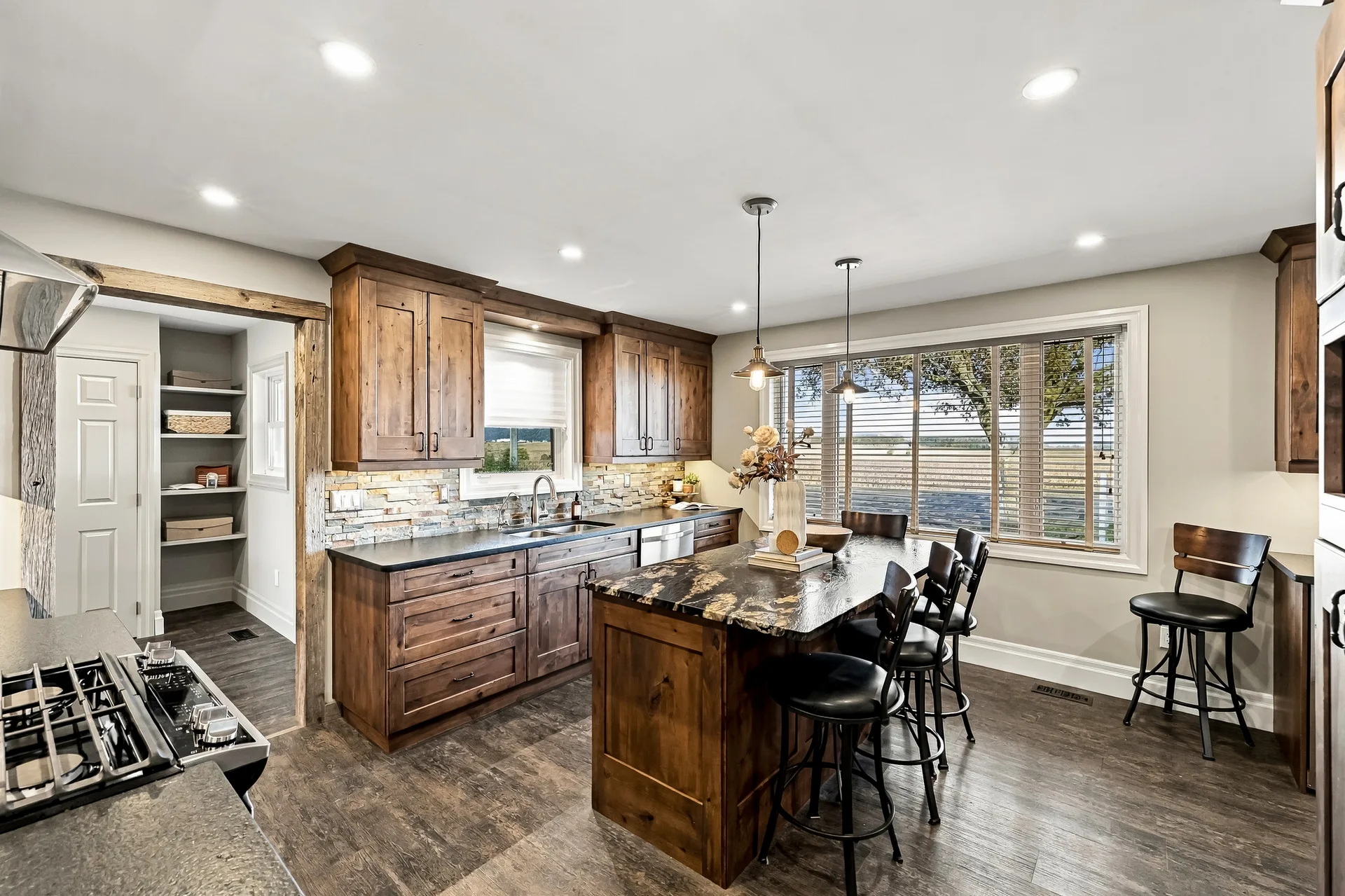 Custom kitchen with rich wood cabinetry, granite island and pendant lights