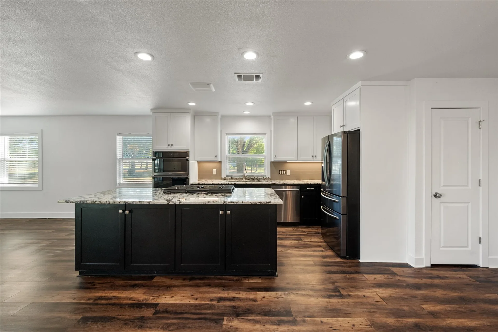 Open-concept kitchen with black island and white cabinetry