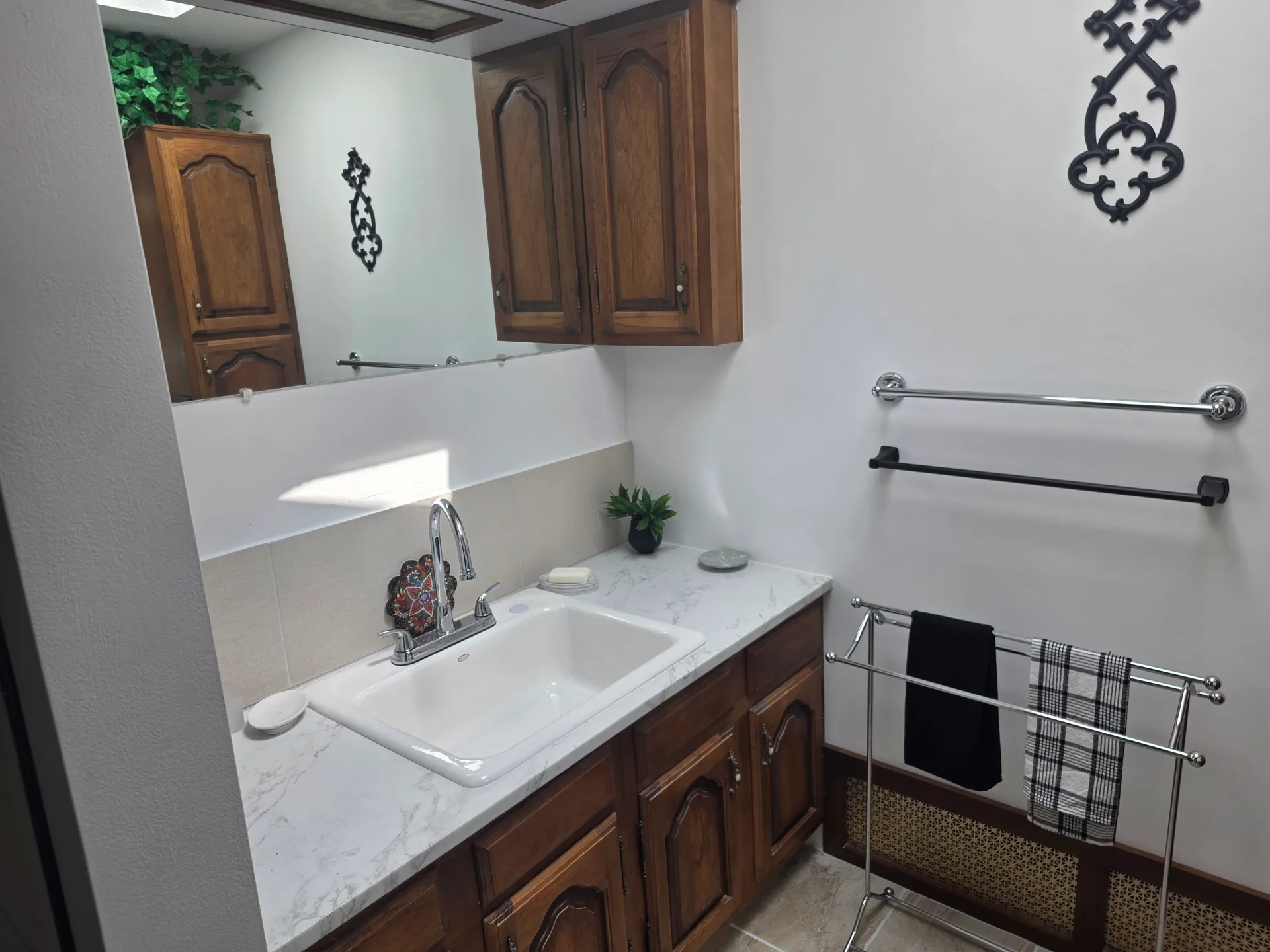 Bathroom with wood vanity, large mirror, and faux-marble countertop