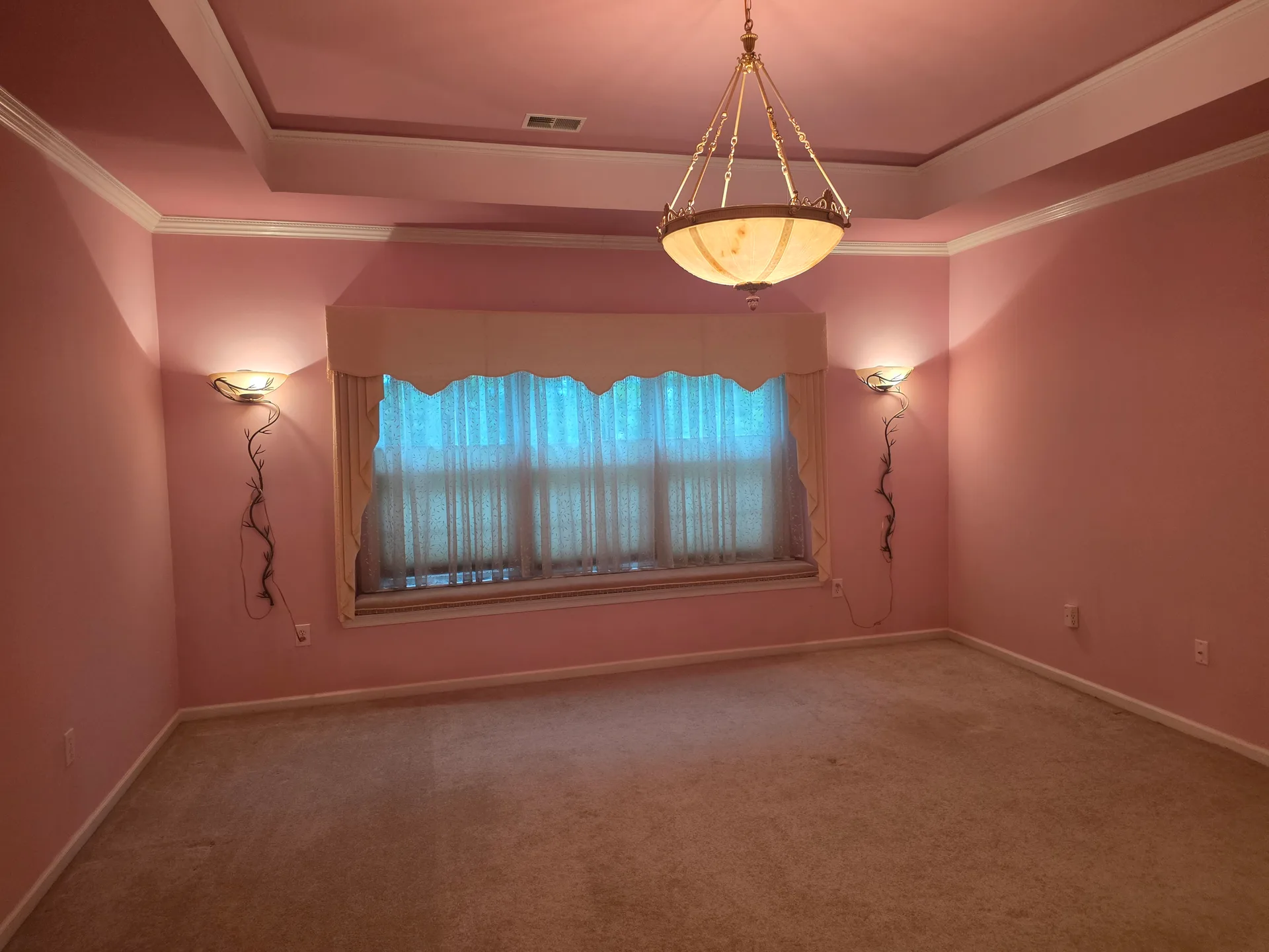 Primary bedroom with tray ceiling, chandelier, and carpeted floors