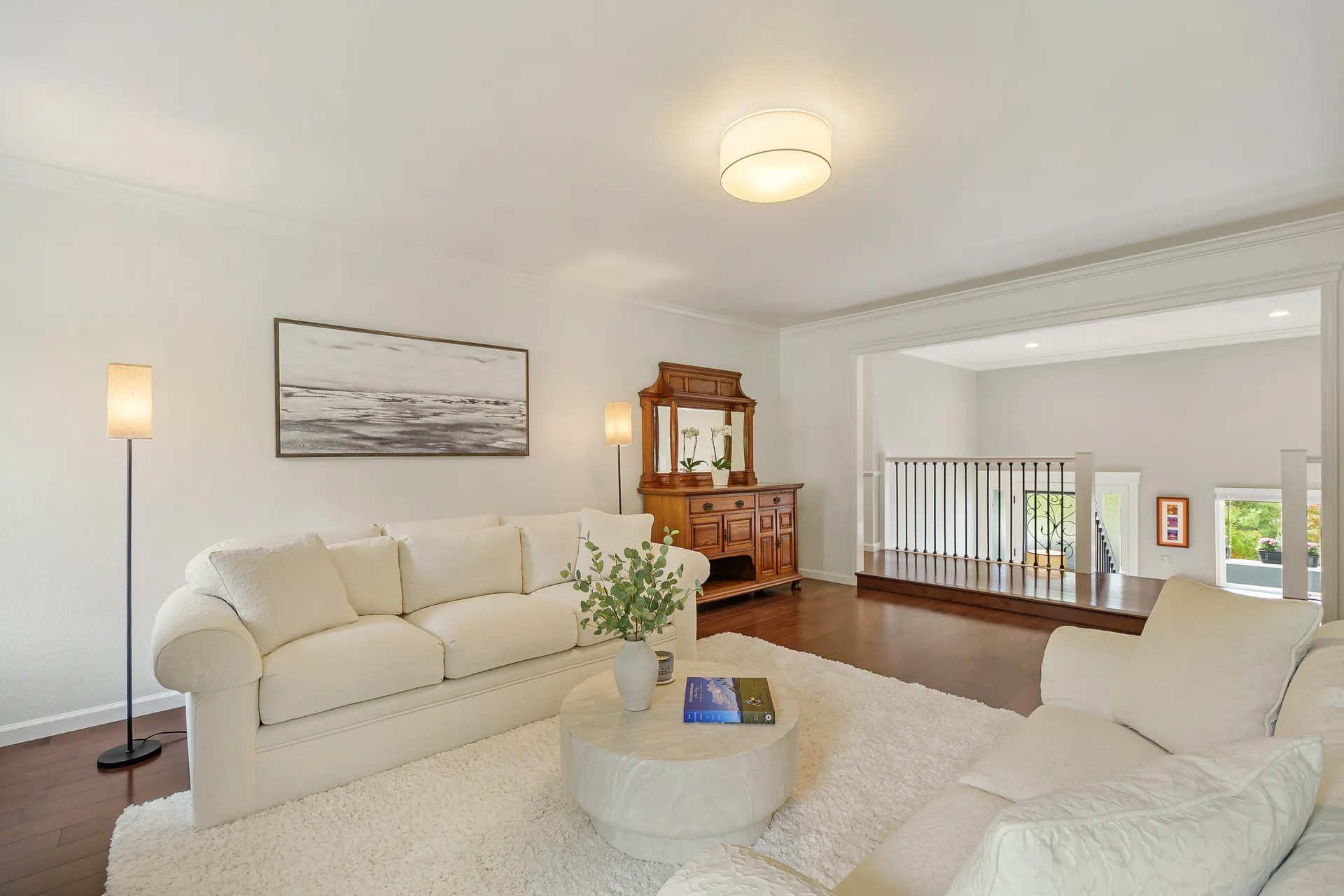 Living room looking toward an elevated landing with railing and hardwood floors
